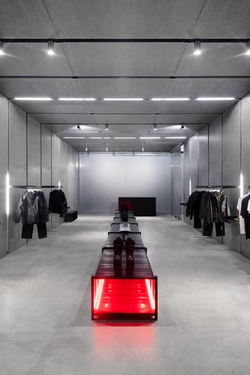 Interno di un locale commerciale allestito con pavimento in cemento e illuminazione a binario